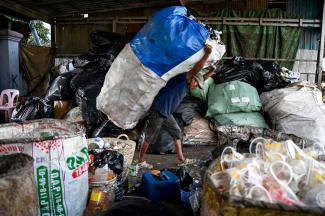 Cette photo montre un travailleur transportant un sac contenant des bouteilles en plastique dans un centre de recyclage en périphérie de Phnom Penh. © Tang Chhin Sothy / AFP
